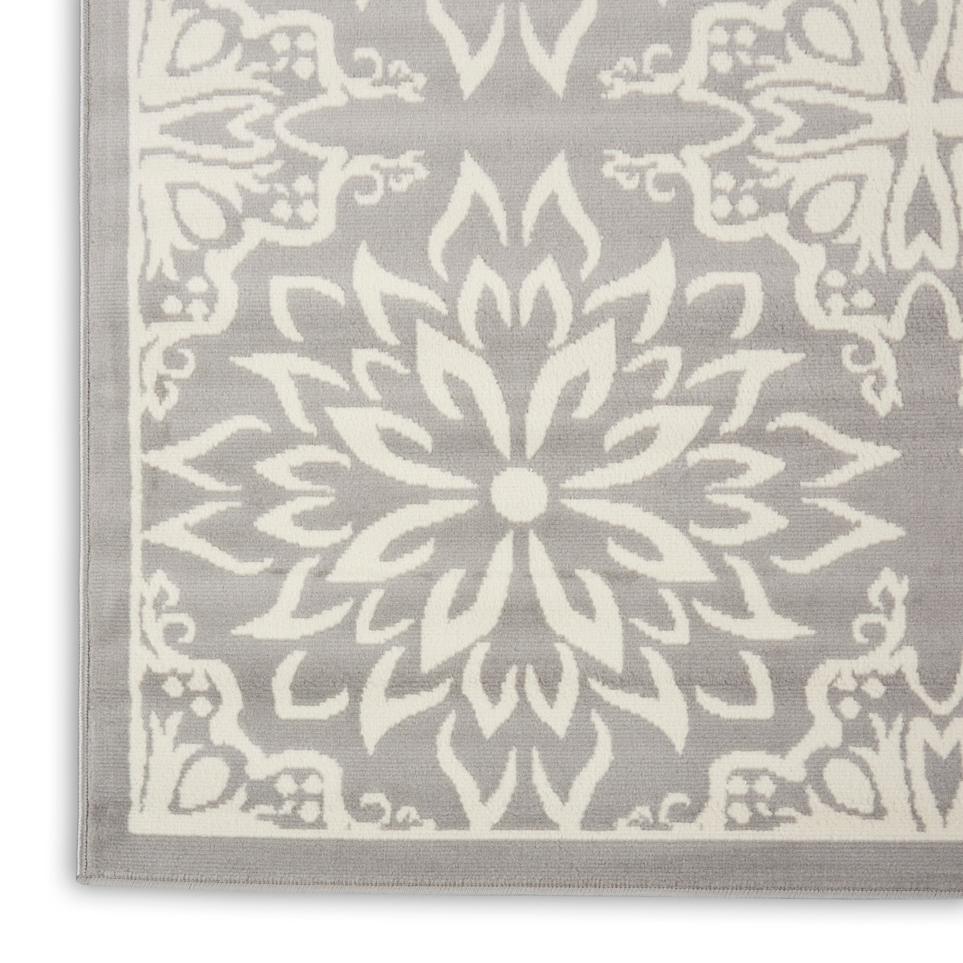 Grey area rug featuring a bold white mandala floral motif with a light border.