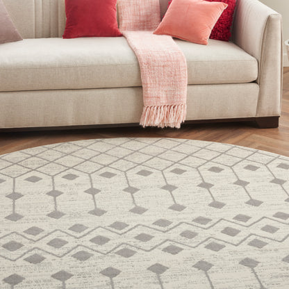 Beige round rug with a light gray geometric pattern on a wooden floor.