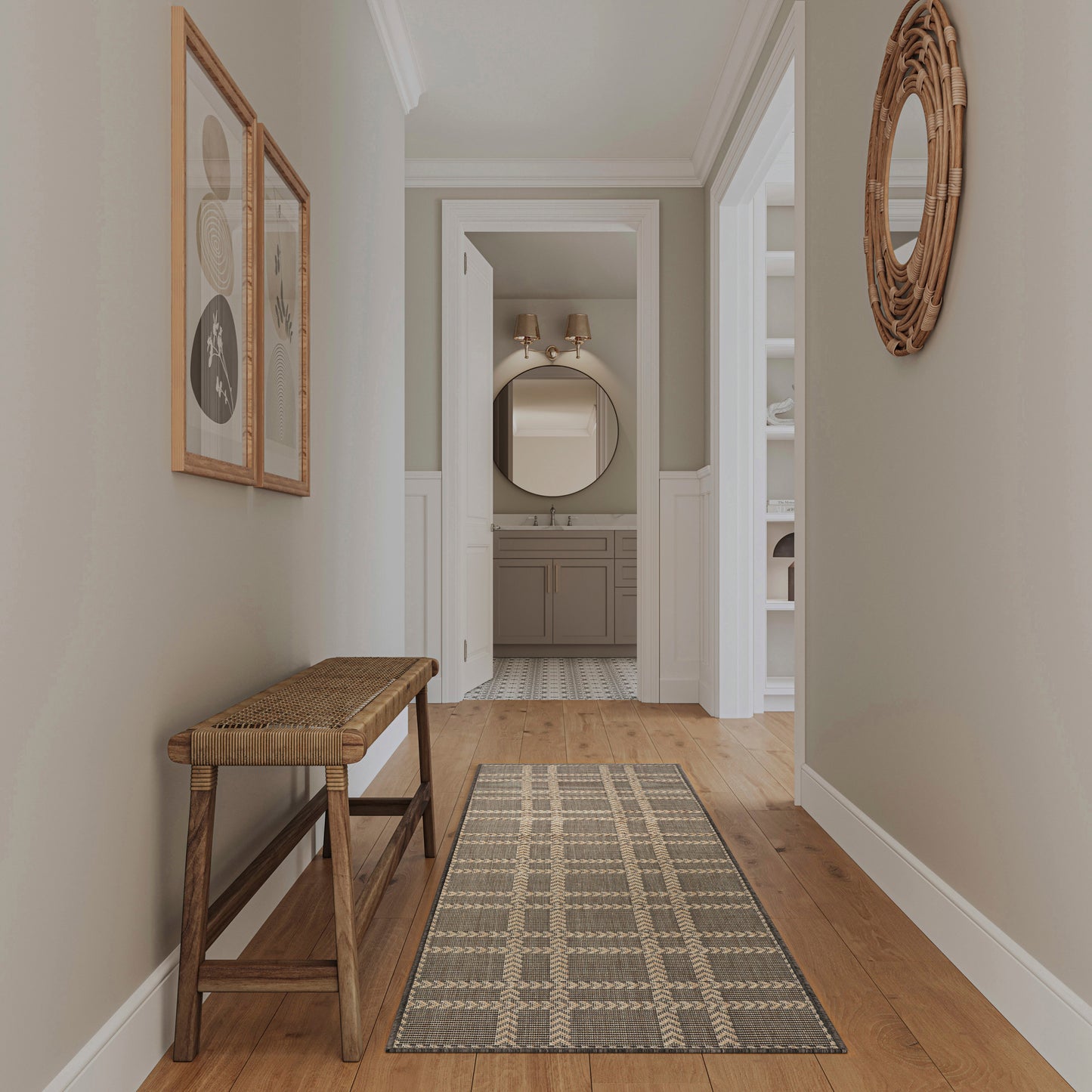 Neutral hallway with wooden bench, geometric woven rug, framed art, round wicker mirror, leads to the bathroom.