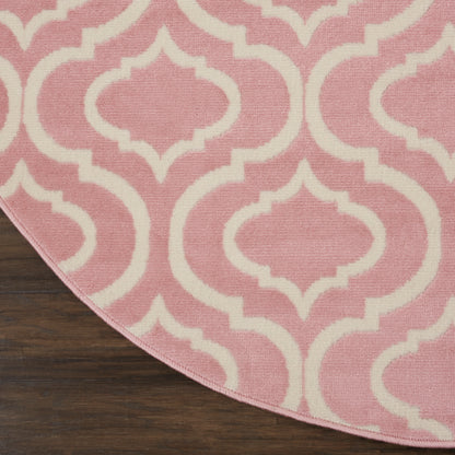Pink rug with white Moroccan-inspired trellis pattern, curved edge on dark wooden floor.