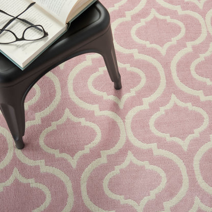Pink rug with white quatrefoil lattice; black small table with an open book and glasses on top.