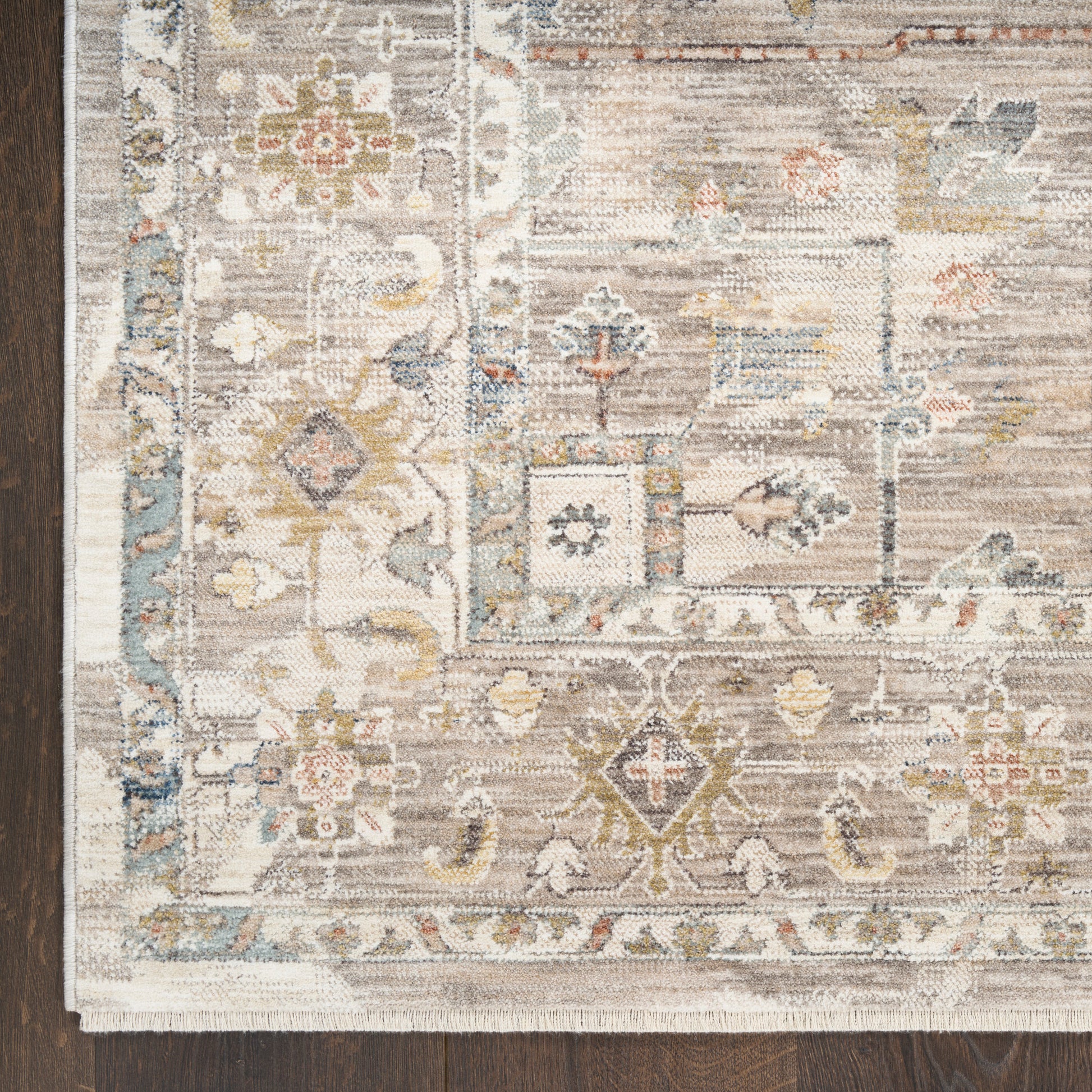 Traditional oriental rug with ivory, blue, and taupe floral motifs on a cream field, fringed border.