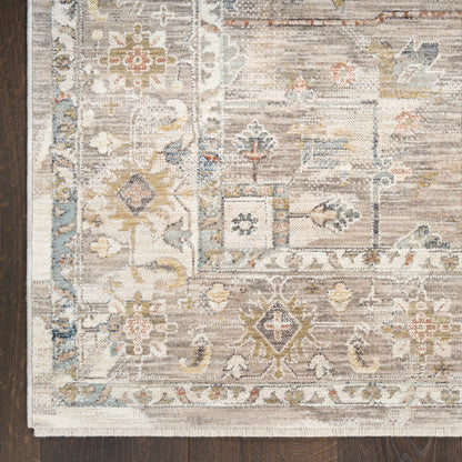 Traditional oriental rug with ivory, blue, and taupe floral motifs on a cream field, fringed border.
