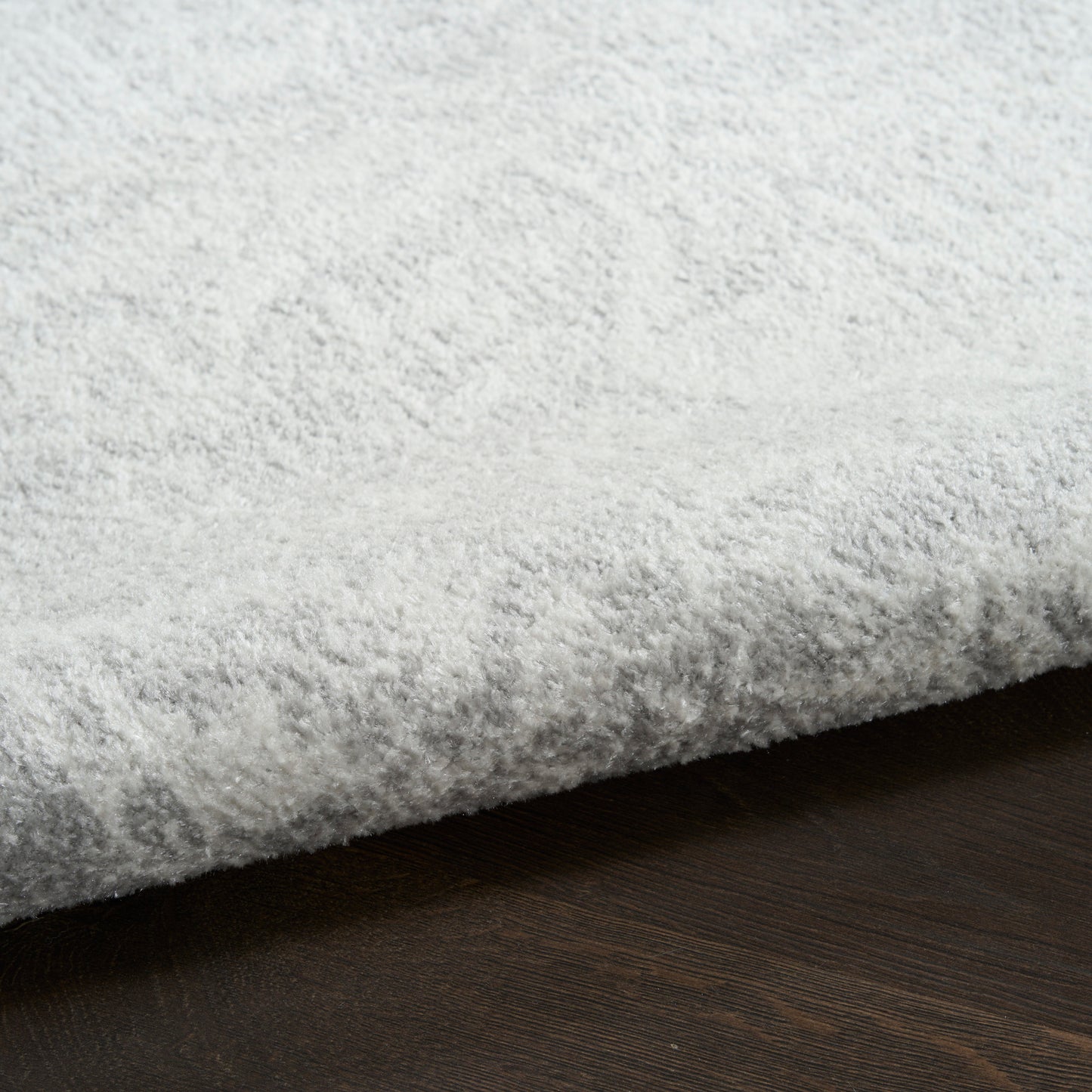 Plush light gray shag rug with high pile on dark wood floor, cozy living room decor.