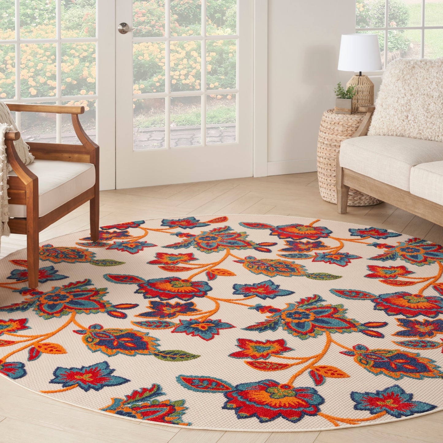 Round floral area rug with ivory backdrop and bright blue, red, orange flowers; woven texture in a bright living room.