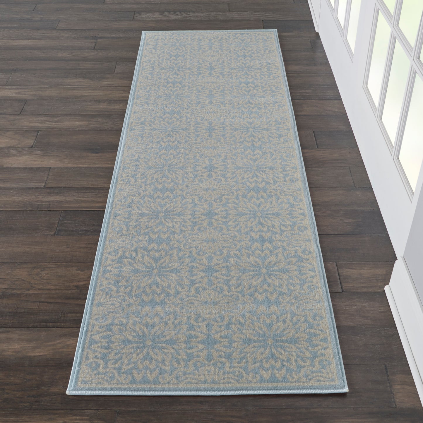 Long runner rug: light beige field with blue damask pattern and a blue border, laid on dark wood floor.
