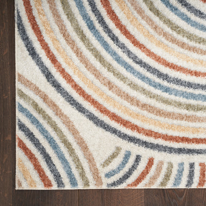 Multicolor curved striped area rug with blues, oranges and beiges on white, laid on dark wood floor