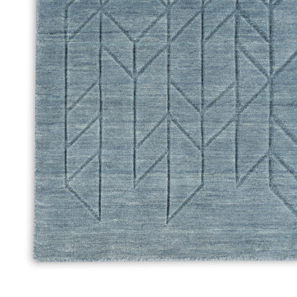 Blue-gray woven rug with subtle geometric diamond chevron lines and textured surface.