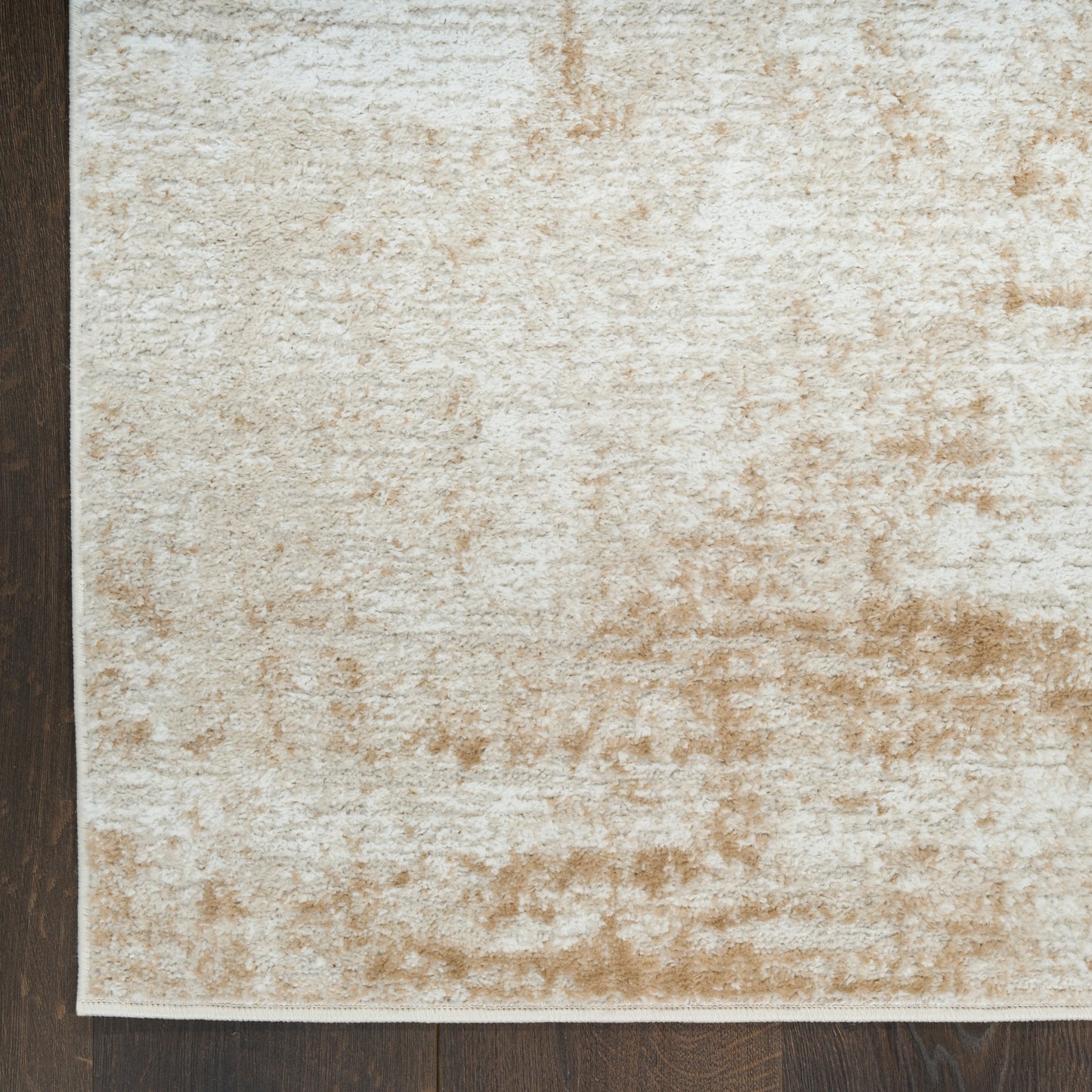 Beige cream abstract area rug with tan accents and soft textured pile on dark hardwood floor.