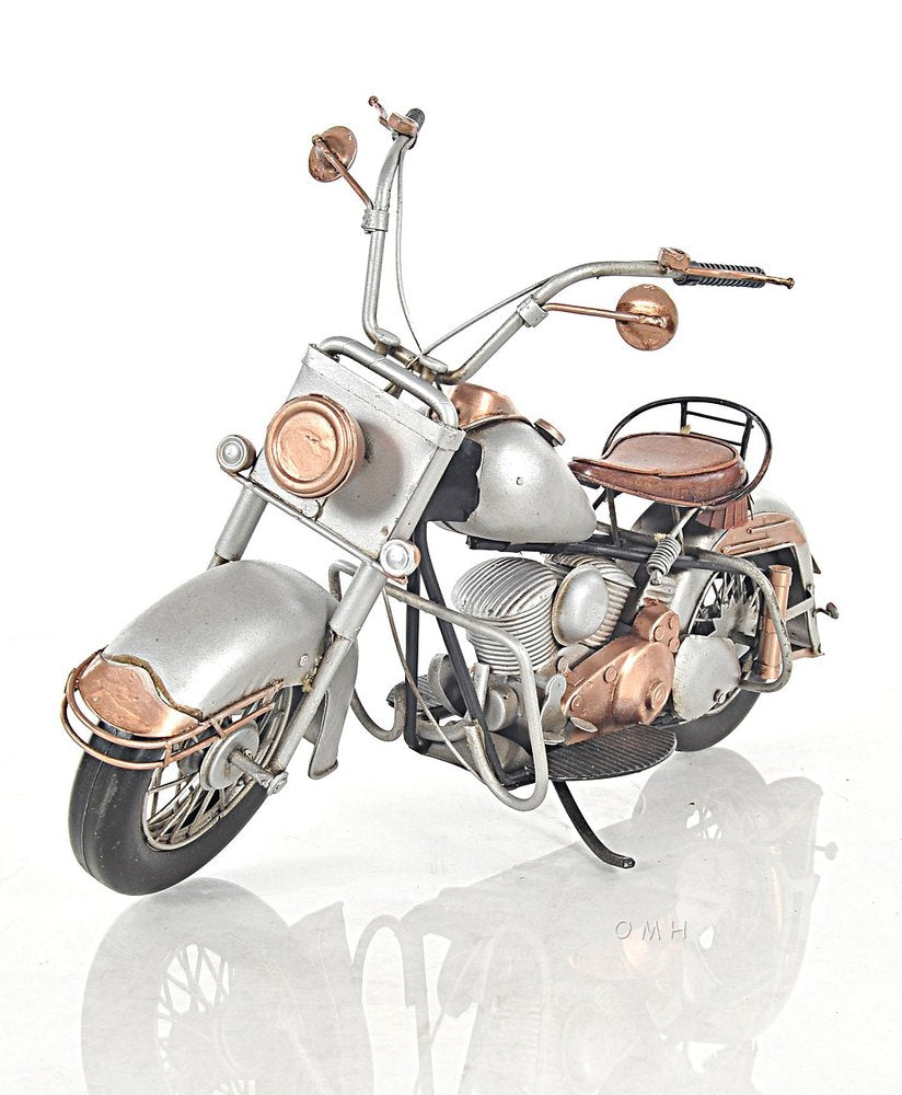 Vintage silver motorcycle with copper accents, brown leather seat, tall chrome handlebars and retro styling.