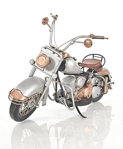 Vintage silver motorcycle with copper accents, brown leather seat, tall chrome handlebars and retro styling.