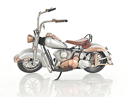Decorative vintage motorcycle model in silver and copper tones, with leather seat and spoked wheels.