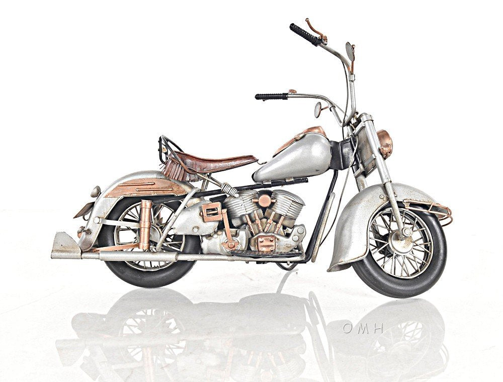 Vintage silver-gray cruiser motorcycle with brown leather seat, chrome accents and rear rack.