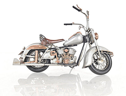Vintage silver-gray cruiser motorcycle with brown leather seat, chrome accents and rear rack.