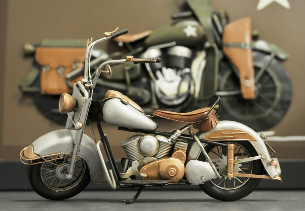 Vintage gray motorcycle with tan leather seat and saddlebags, chrome details, retro cruiser style.