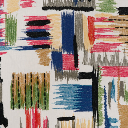 Abstract geometric pillow pattern with multicolor brushstroke blocks in blue, red, green, black on a light background.