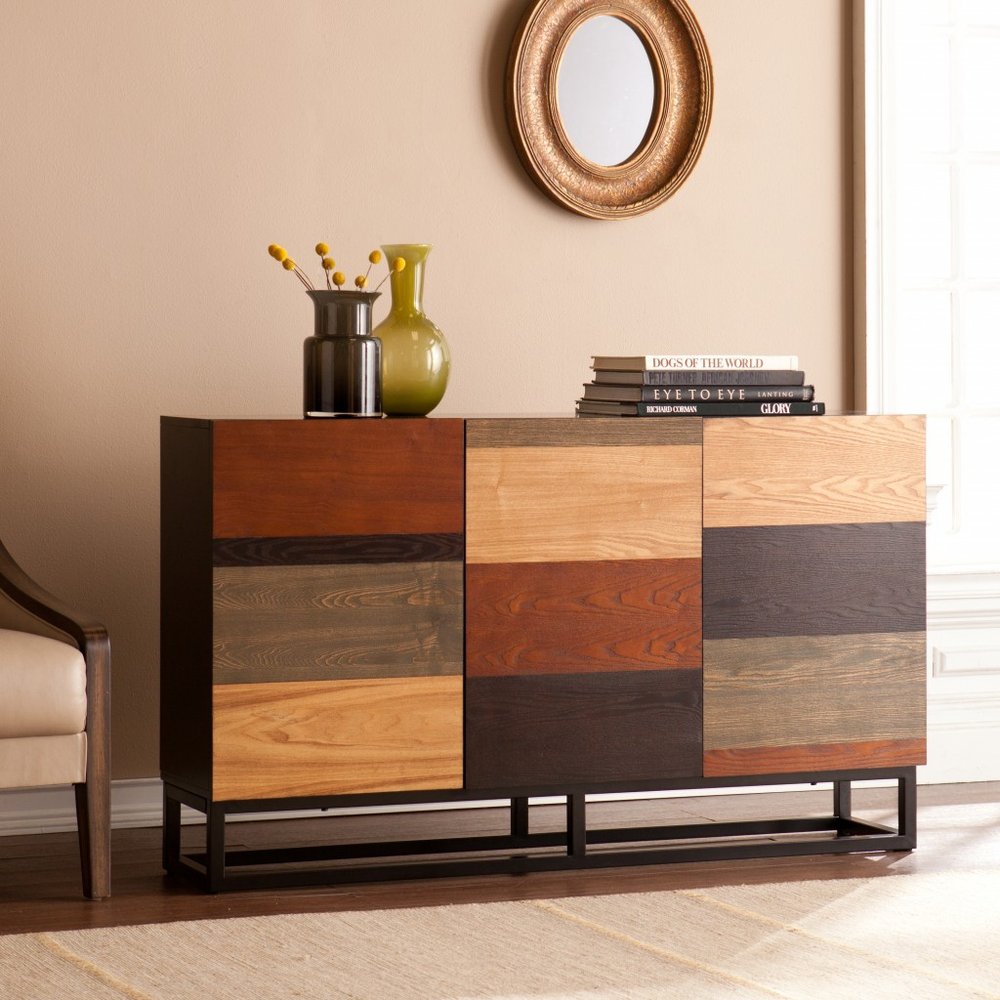 Patchwork wood sideboard with a black metal base, warm-toned panels, top decor vases and books, gold round mirror above