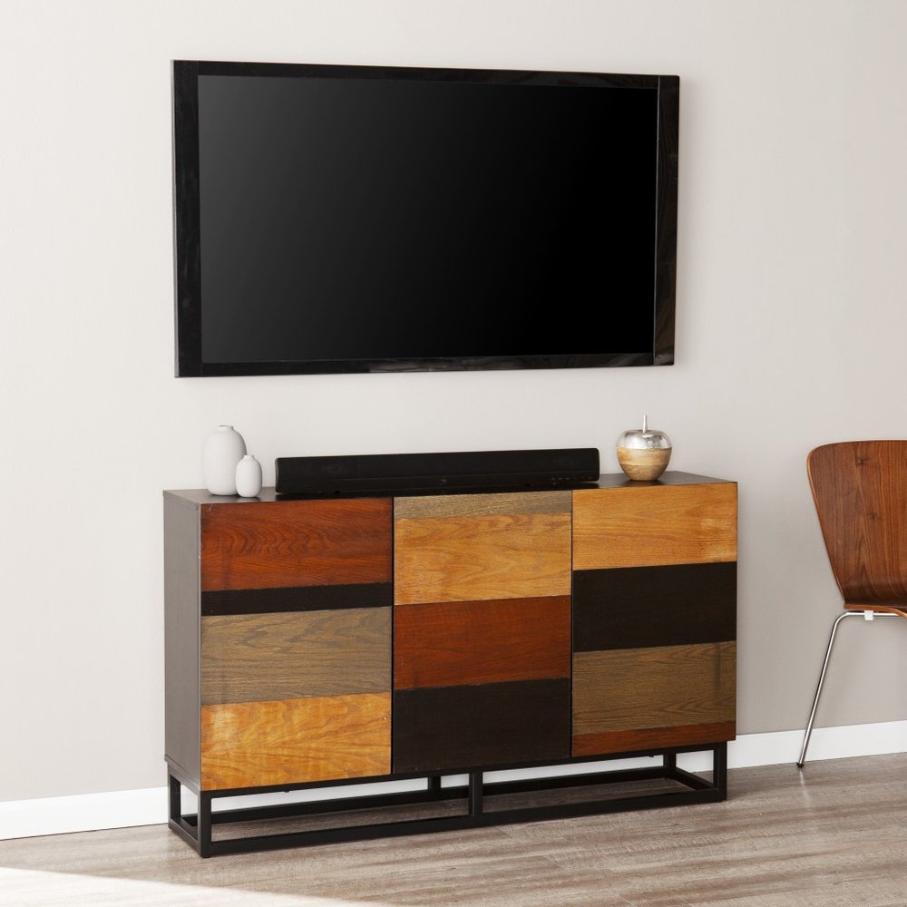 Patchwork wood sideboard on a black metal base with multi-tone drawers, under a wall-mounted TV.