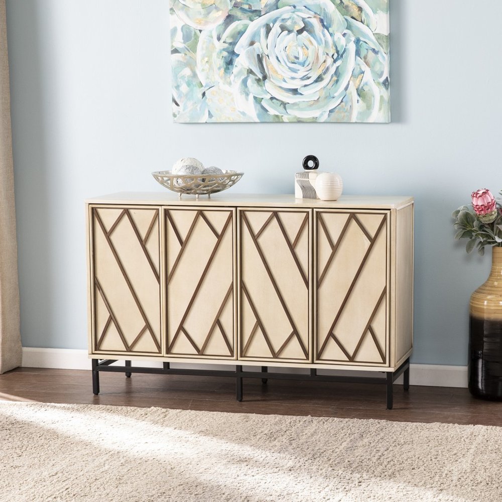 Beige rectangular cabinet with diamond-pattern doors on a black metal base, topped with bowls, against a blue wall.