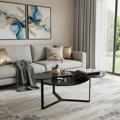 Modern living room with light gray sectional, gold cushions, black two-tier round coffee table, blue-gold abstract wall art, and large window with sheer curtains.