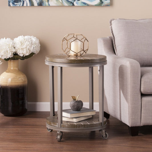 Round industrial metal side table on casters; two-tier, top candle holder, bottom books, beige living room.