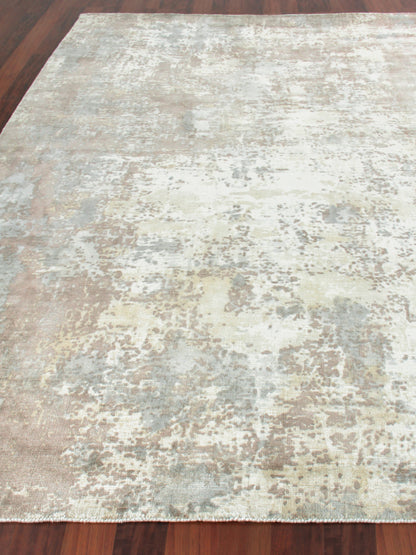 Distressed abstract area rug with ivory, gray, beige and pale yellow tones on a wooden floor.
