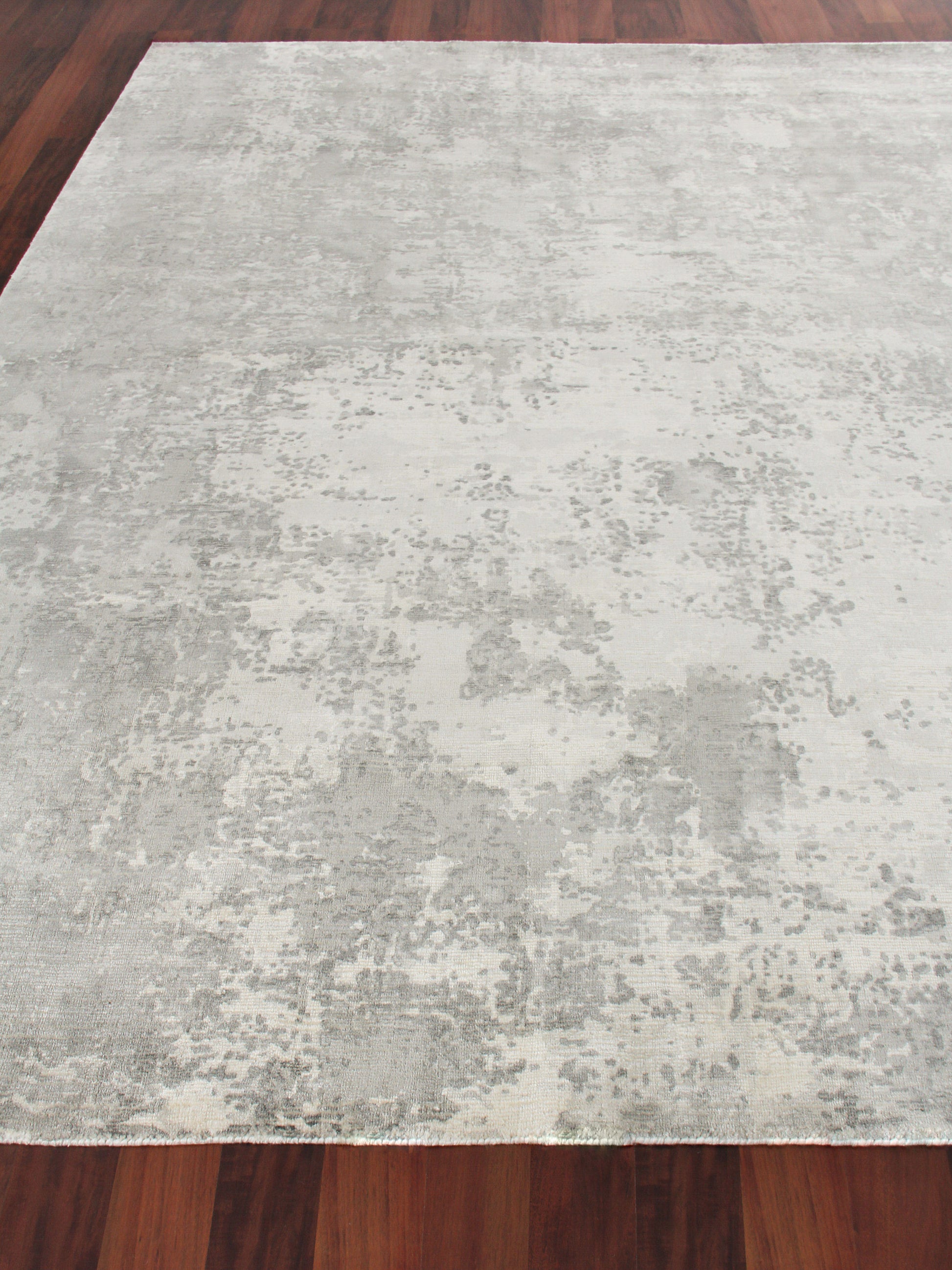 Light gray distressed area rug with abstract pattern on dark wood floor