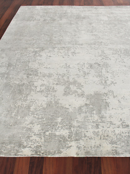 Rectangular light gray and cream indoor hand loomed area rug, 4' x 6', with an abstract washed pattern on a dark wood floor.