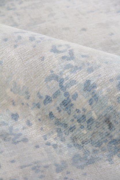 Close-up of a beige rug with blue-gray abstract pattern and soft, textured pile.