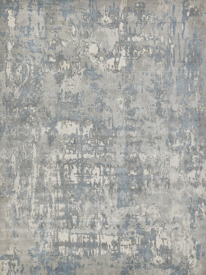 Abstract distressed area rug in blue, gray and cream tones with a painterly, irregular pattern.
