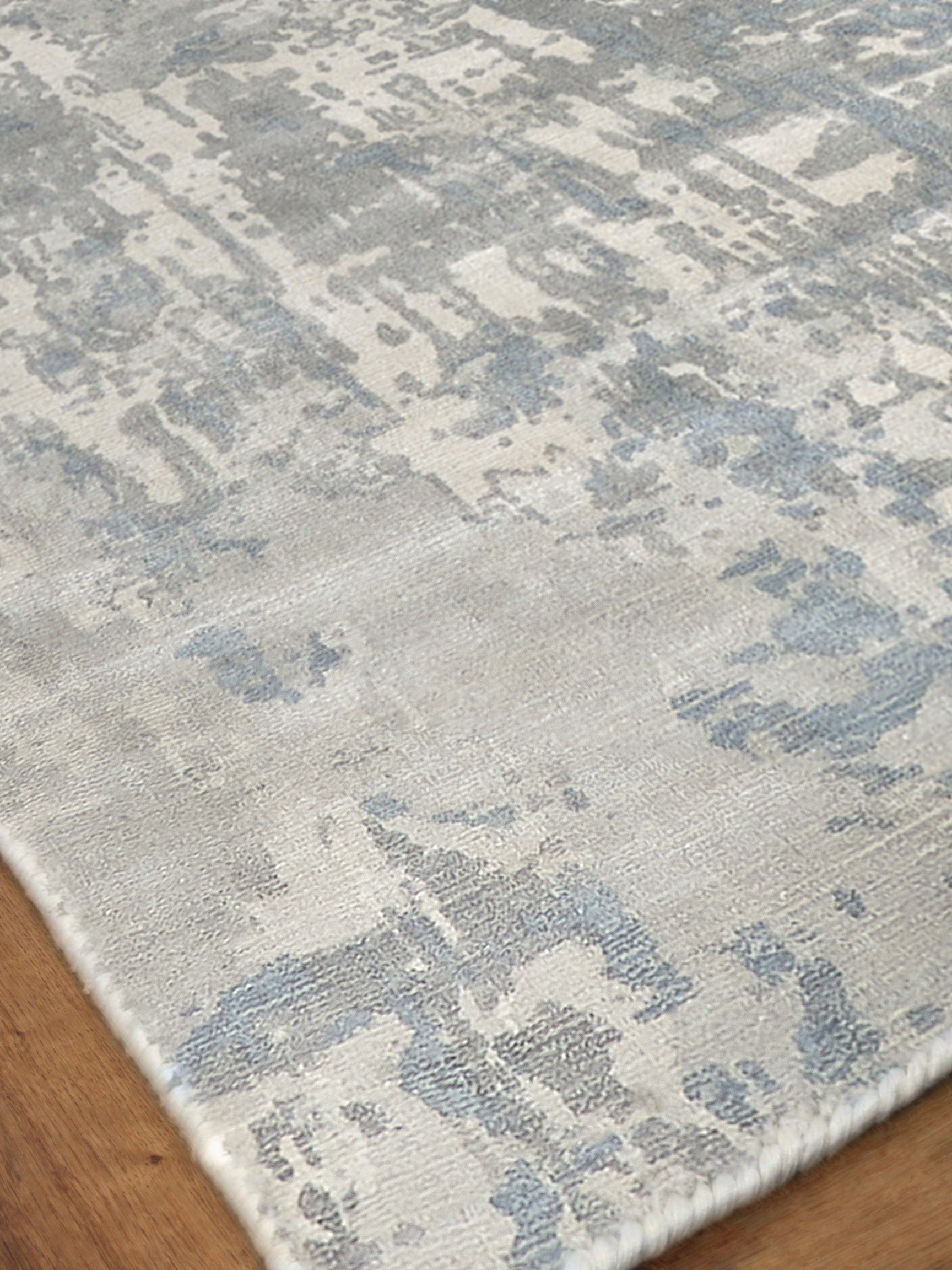 Abstract blue-gray and cream area rug with distressed pattern, soft pile, rectangular on wood floor.
