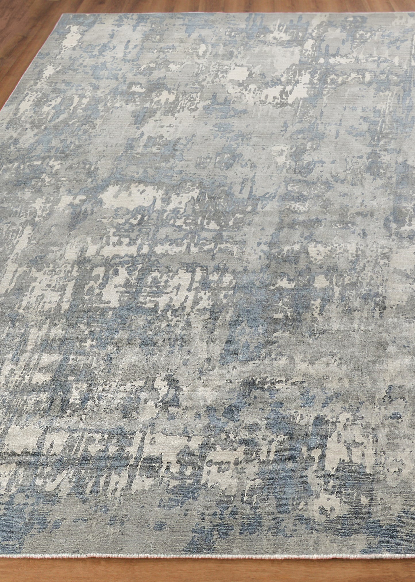 Blue-gray abstract distressed area rug with painterly patches on a light beige field.