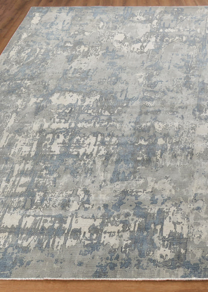 Blue-gray abstract distressed area rug with painterly patches on a light beige field.