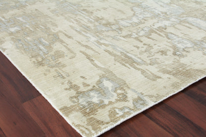 Beige abstract-pattern area rug with cream, taupe and light gray tones, fringed edge on dark hardwood floor.