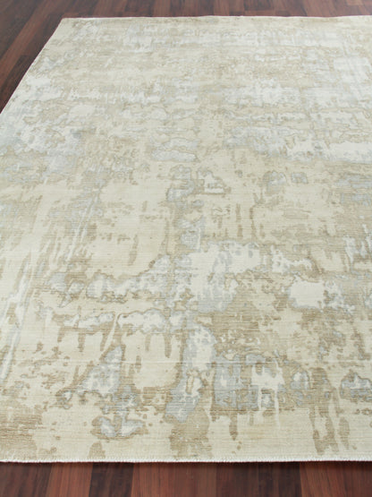 Rectangular beige distressed area rug with subtle gray-blue floral medallion pattern on hardwood floor.