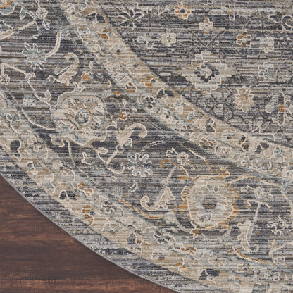 Round area rug in blue-gray with ivory and beige floral arabesque pattern on dark wood floor