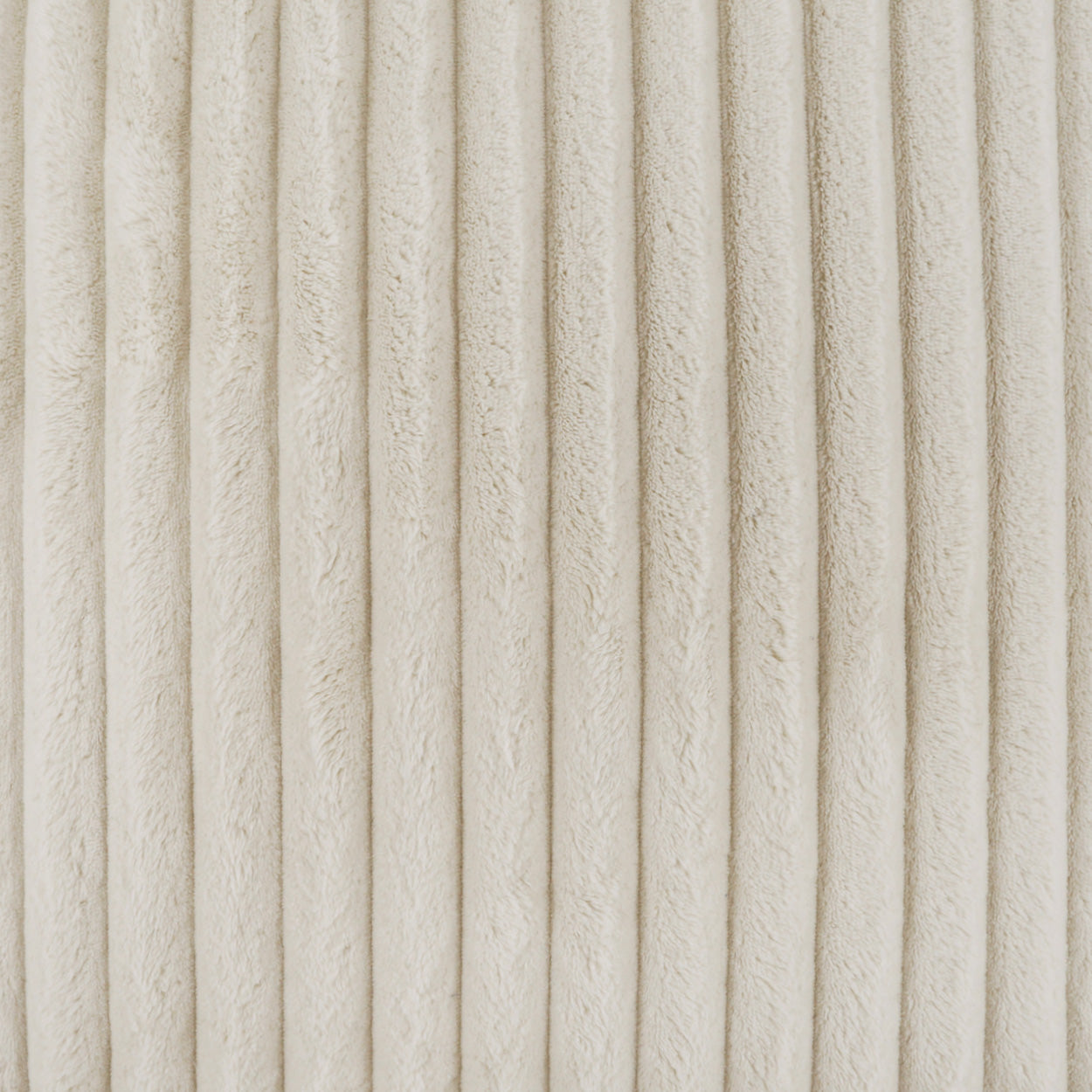 Cream corduroy fabric close-up with vertical ribs; plush textured textile for clothing or upholstery.