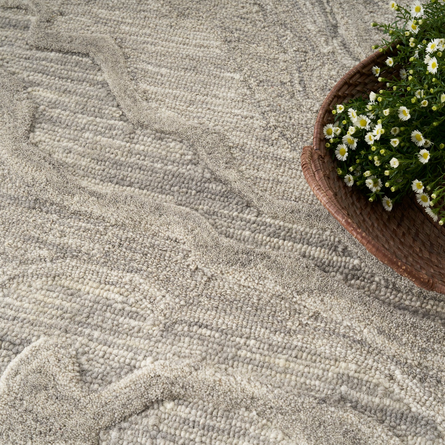 Beige textured rug with a wavy pattern; brown wicker basket of white daisies sits at the top-right.