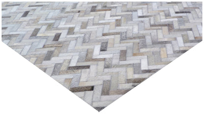 Mosaic leather rug for indoor use, hand-stitched patchwork in ivory, beige and gray tones with a zigzag pattern.