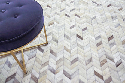 Purple round tufted ottoman with gold metal legs on a beige chevron rug.