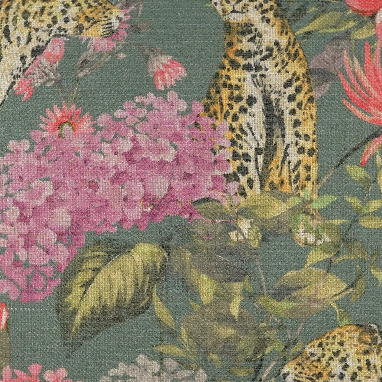 Green fabric with yellow leopard spots and pink florals in a lush jungle print.