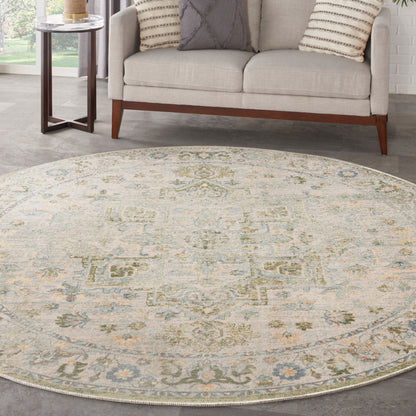 Round ivory rug with pale blue-green and yellow medallion motif under a beige sofa and wood side table.