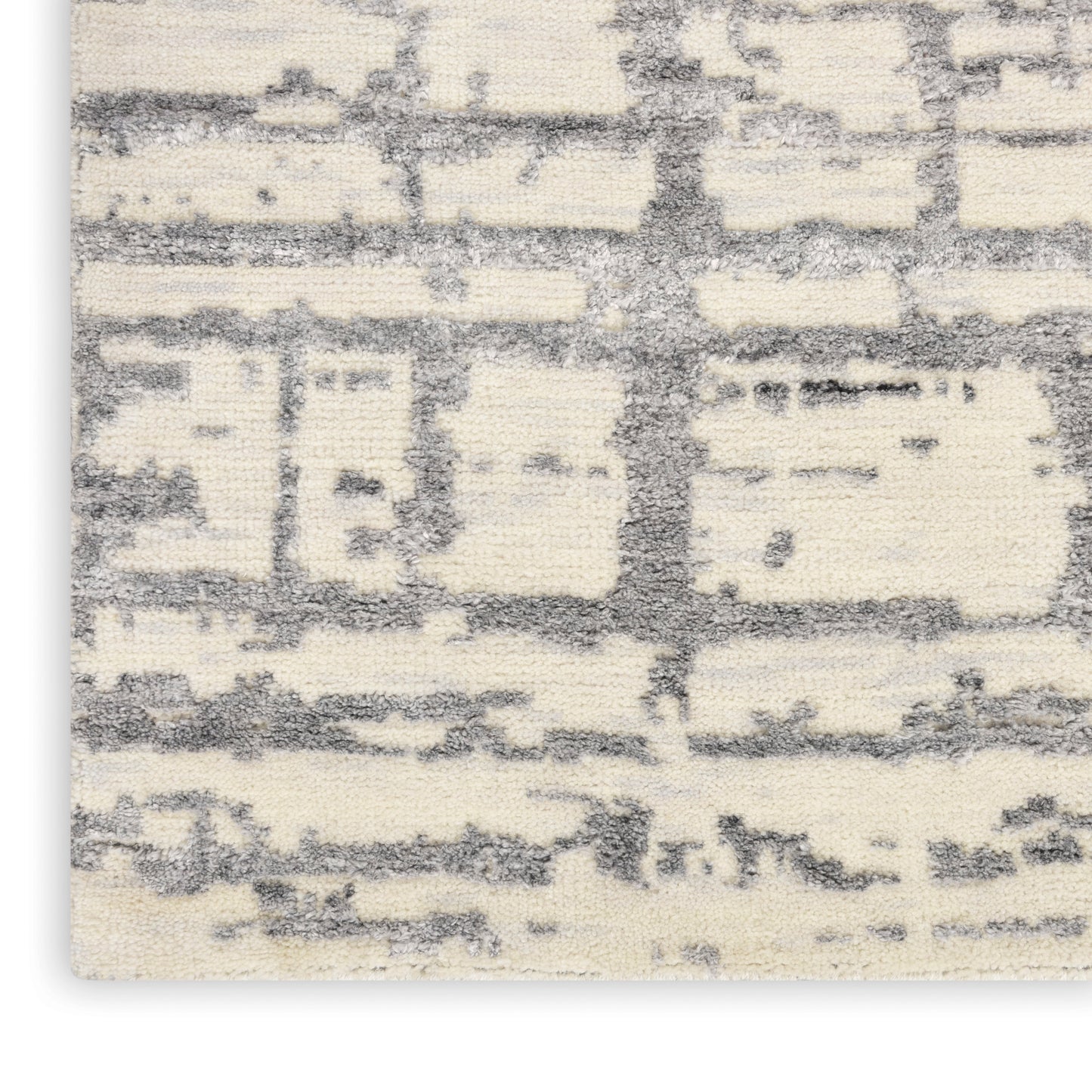 Cream and gray abstract rug close-up with textured pile and geometric block pattern.