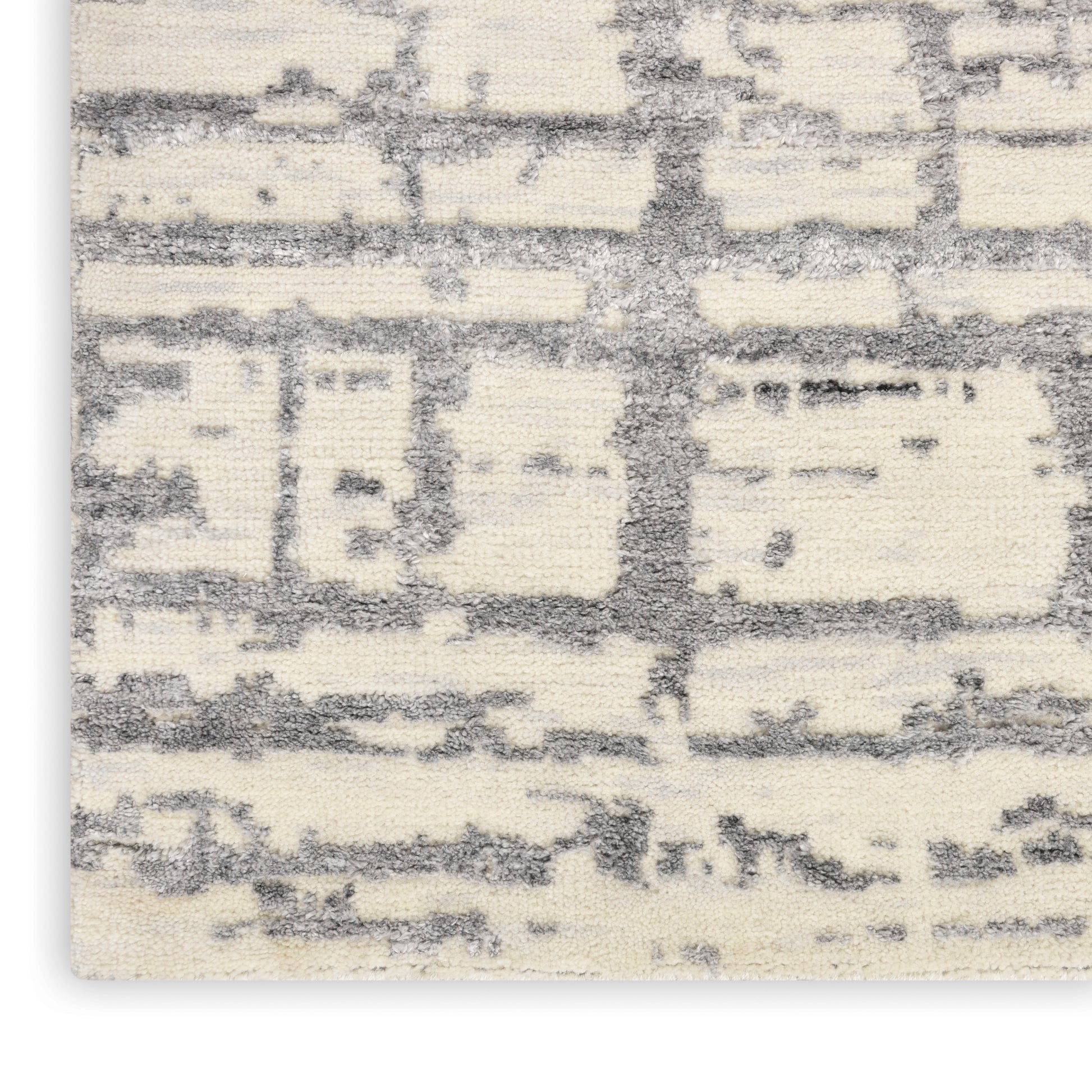 Cream and gray abstract rug close-up with textured pile and geometric block pattern.