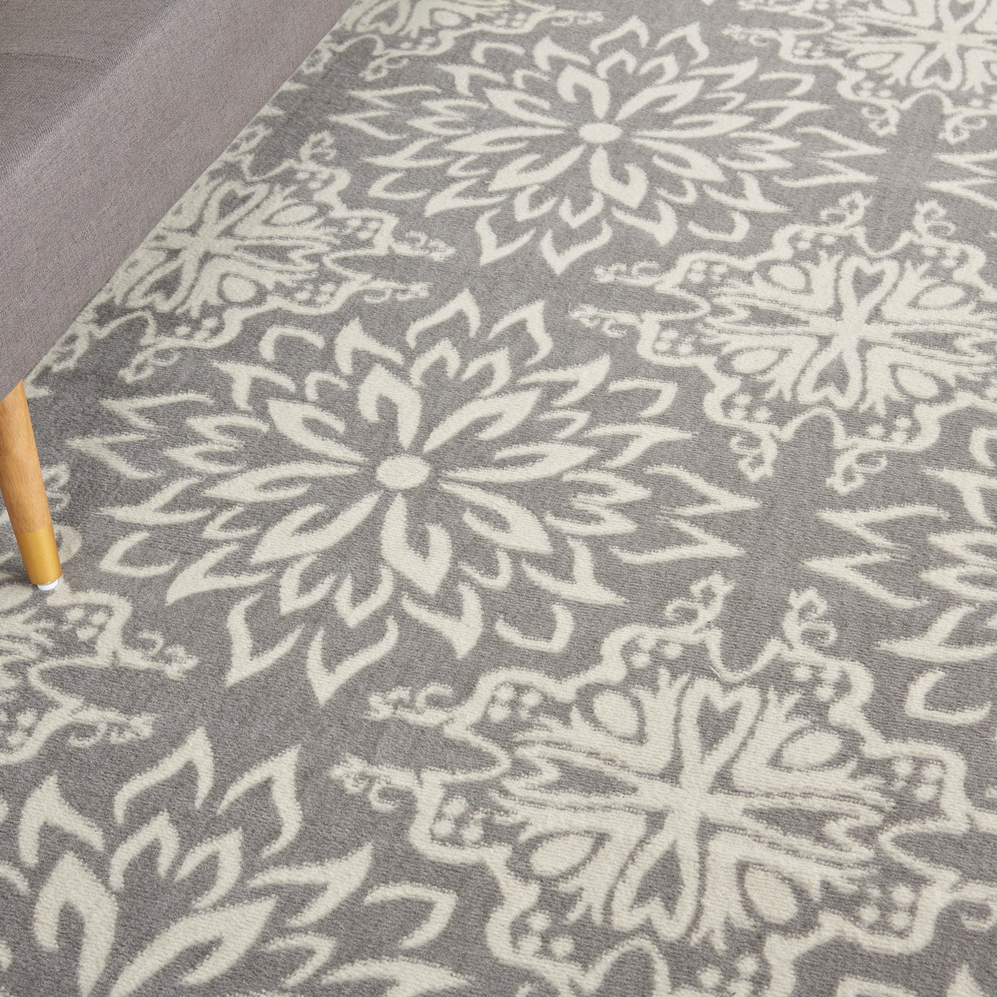 Grey area rug featuring large white floral medallion motifs in a damask-style pattern.