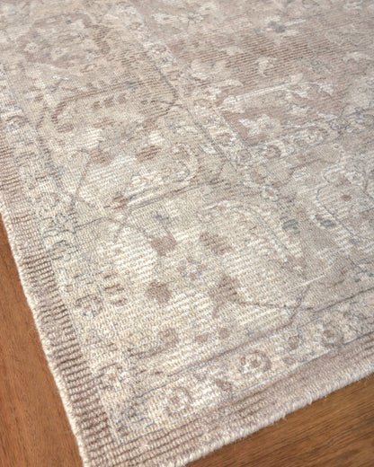 Beige distressed oriental patterned area rug with ornate borders on wooden floor.