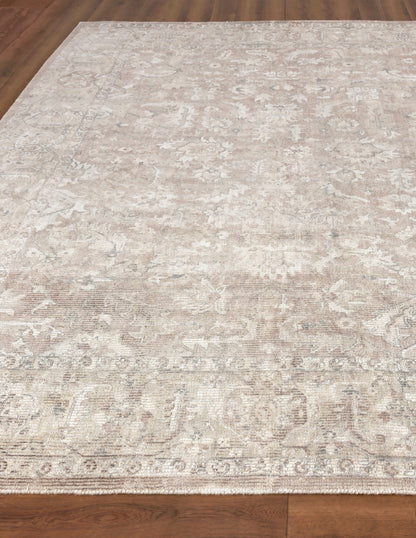 Beige distressed oriental area rug with muted cream and taupe floral motifs on a wooden floor.