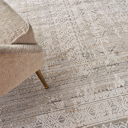 Beige boucle chair with rounded arm and tapered wooden leg on a light gray geometric rug.