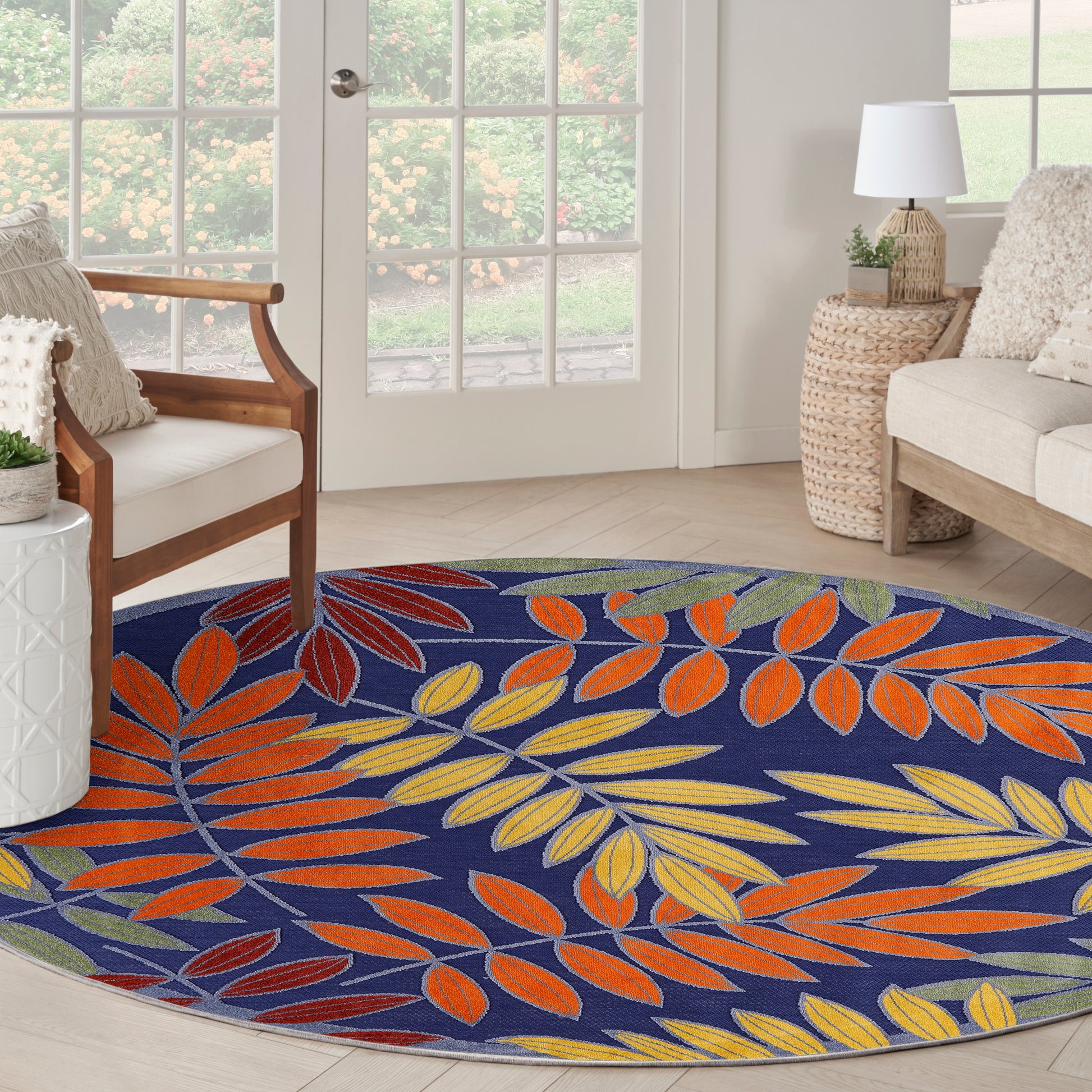 Round blue rug with orange, yellow, and green leaf pattern in a bright living room.