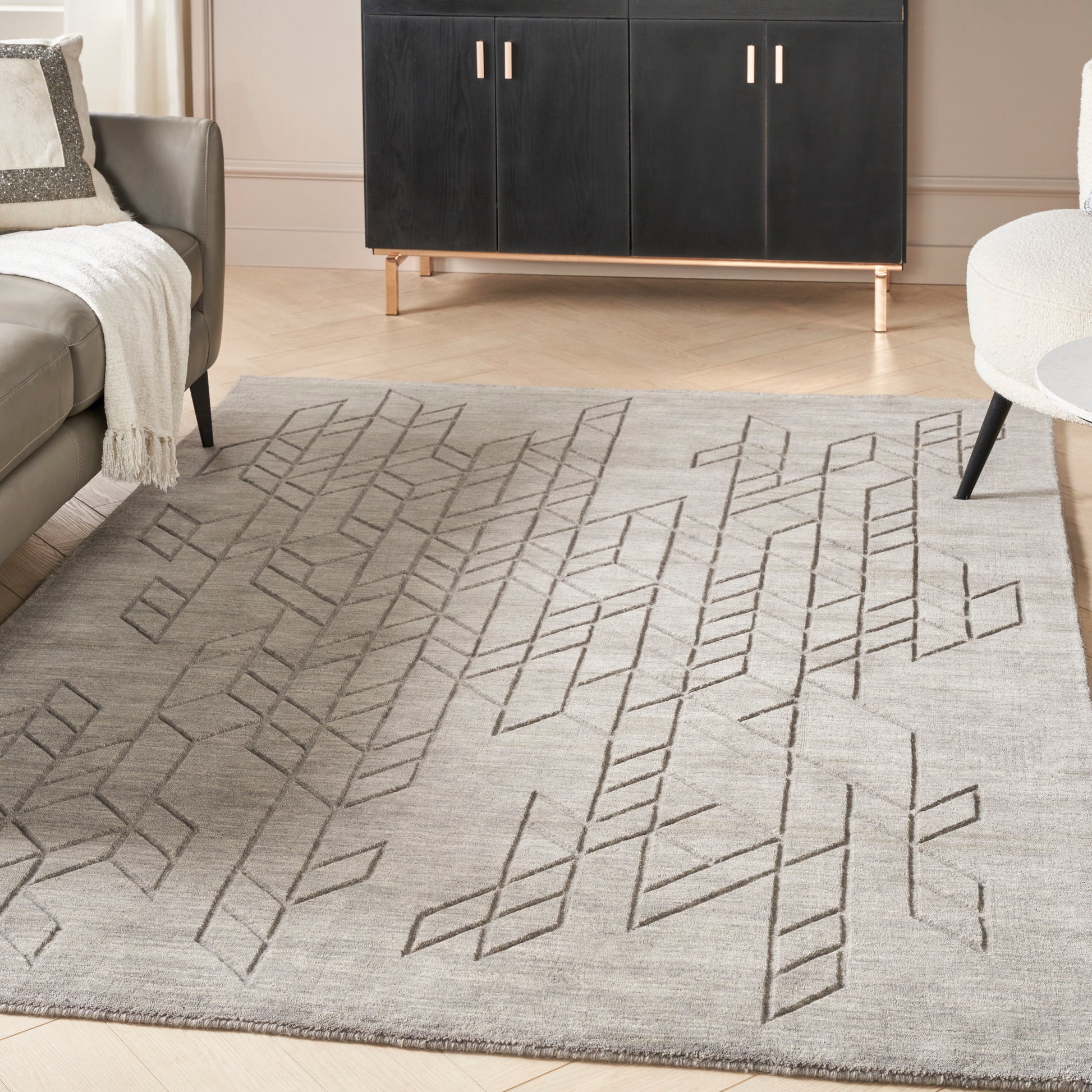 Light gray flatweave rug with dark geometric diamond lattice; modern living room with black cabinet and beige sofa.